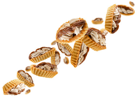 Two types of cream filled tartlets fly through space forming a chain shape. Isolated on whiteの写真素材