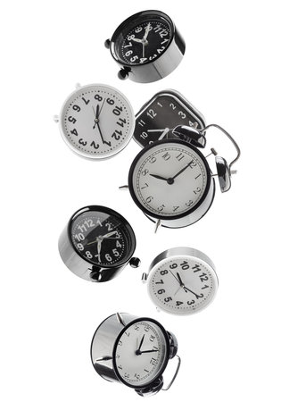 Beautifully retouched different alarm clocks falling in space. Isolated on white