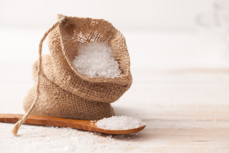 sea salt in the bag and wooden spoon on white wooden backgroundの写真素材