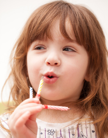 girl blows out the three candles in your handsの写真素材