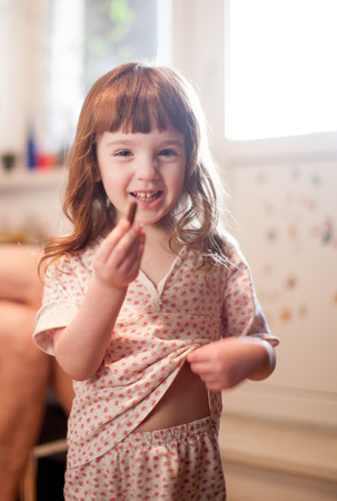 girl in pajamas in the morning to try a piece of foodの写真素材