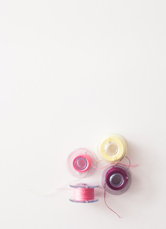 Colored thread coils on white background, sewing, place for text