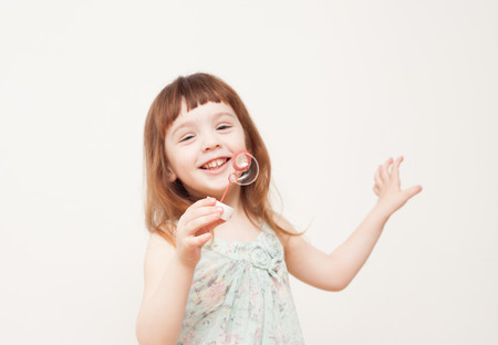 A cheerful girl (3-4 years old) with red hair playing with soap bubbles.の写真素材