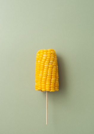 Cooked on the cob boiled corn on a stick on pastel background. Background image. Place for text.の写真素材