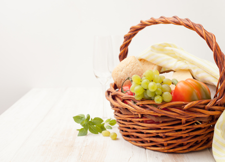 A basket of grapes, vegetables, bread, cheese and drinks on white backgroundの写真素材