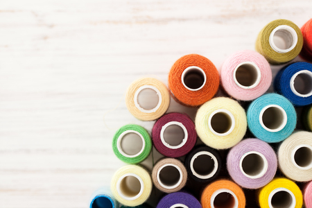 A lot of sewing colored thread on a white table. The view from the top.