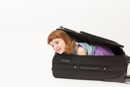 The girl is going on a trip with a large black suitcase on a white background. An empty space to insert text.の写真素材