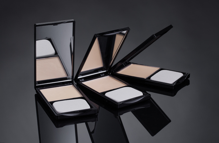 Template for advertising cosmetic decorative means. Black background with three outdoor compacts. The place to insert the text.の写真素材