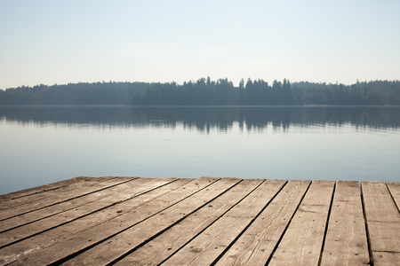 Rest on the forest lake. View from the shore of the fishing lake in the early morning in the fog. Place for text.の写真素材