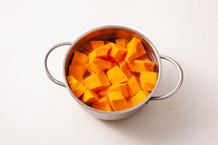 Cut into pieces raw pumpkin on wooden light background. Copy space text.の写真素材