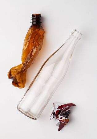 Trash items a crumpled plastic bottle, glass and a lump of paper on a whiteの写真素材