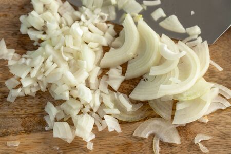 The cook cutting and dice onion on a wooden chopping board. Closeup.