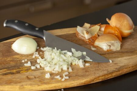 The cook cutting and dice onion on a wooden chopping board.の写真素材