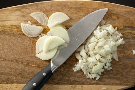 The cook cutting and dice onion on a wooden chopping board. Closeup.の写真素材