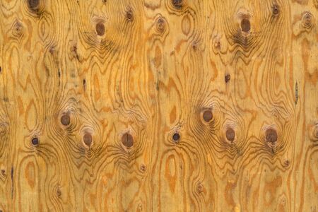Background image texture of old plywood with dark streaks streaks and knots