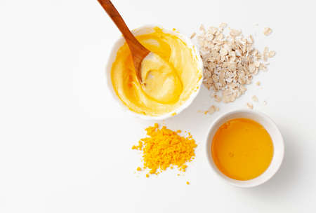 Preparation a rejuvenating homemade face mask made of turmeric, honey and oatmeal on a white background. Copy space text.の写真素材