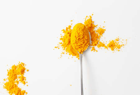 Bright yellow aromatic spice turmeric for health and beauty. A pile of turmeric spice powder in a spoon on a white background. Copy space text.の写真素材