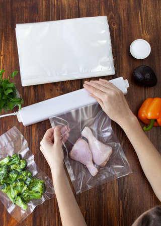 The process of packing raw chicken legs in a vacuum bag and sealing with a vacuum cleaner on a...