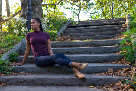 a woman sitting on stone steps in a parkの写真素材