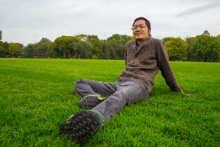 an asian man in his twenties relaxing in a parkの写真素材
