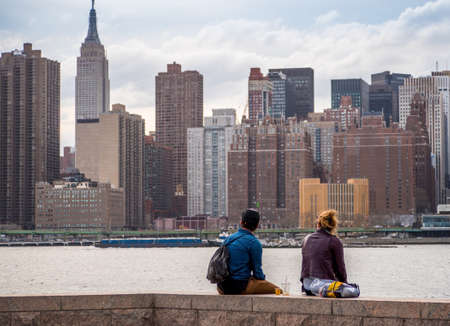 A young man and woman looking at Manhattan skyline in New York Cityの写真素材