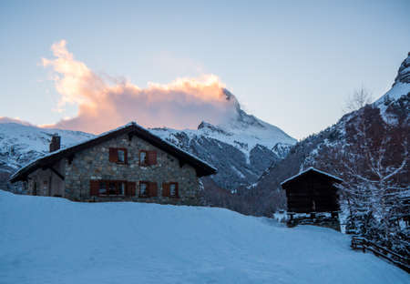 Stone Swiss chalet with the Matterhorn in the background engulfed in cloudsの写真素材