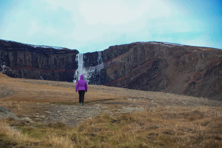 Woman walking towards Hengifoss waterfall, East Icelandの写真素材