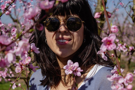 Caucasian woman among the pretty pink peach blossoms, in Lleida, Spain.