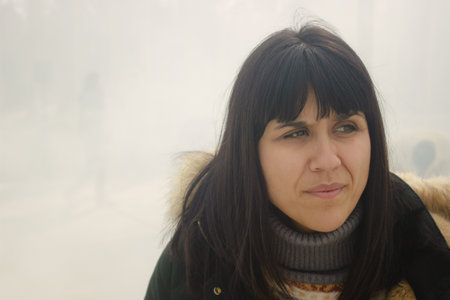 Pretty European girl posing among the fog on a winter day