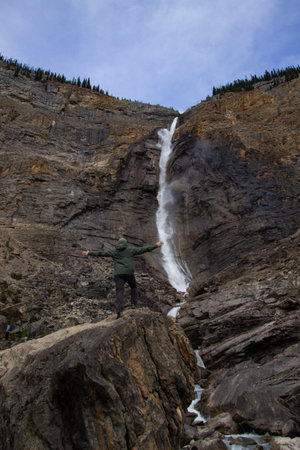 Male hiker posing in front of Takakkaw Falls