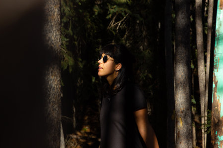 Woman with sunglasses walks between trees.