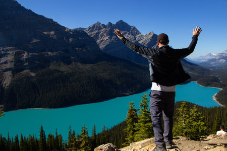 Hiker man with arms up. On a clear autumn sunny day at the beautiful Peyto Lake with turquoise water.の写真素材
