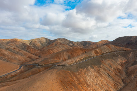 Aerial perspective of a curvy asphalt road leading towards the dramatic slopes of Sicasumbre Mountain.の写真素材