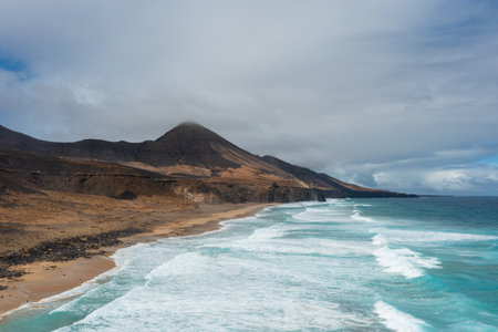 Scenic aerial panorama of Cofete Beach, golden sand dunes, and Roque del Moro in the background.の写真素材