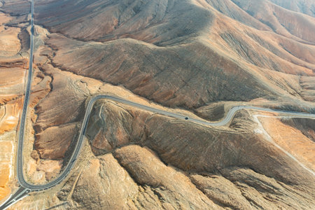 Stunning overhead view of a twisting mountain pass in the barren, sunlit scenery of Fuerteventura.