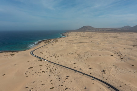 Drone shot of the highway cutting through desert-like dunes with the Atlantic Ocean in the background, Corralejo Natural Park.の写真素材