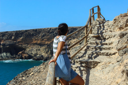A woman rests on the railing along the trail to the Ajuy Caves in Fuerteventura, enjoying a peaceful...
