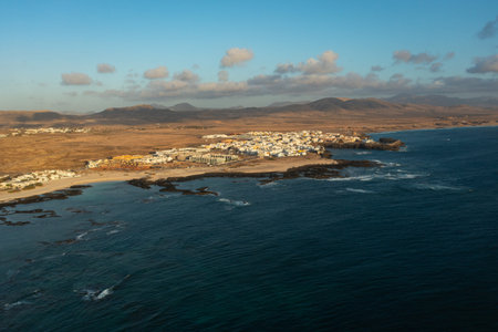 High-angle drone shot of El Cotillo and surrounding beaches at sunset, showing volcanic coastline, clear waters, and traditional seaside town in Fuerteventura, Canary Islands.の写真素材