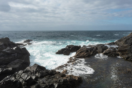 Top-down aerial view of the famous natural swimming pools of Aguas Verdes in Fuerteventura. Waves...