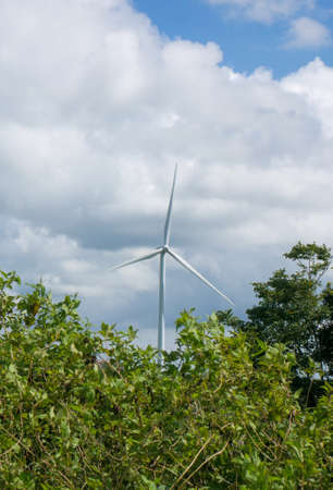 Wind turbines on the green hilly terrain with the bright blue sky.