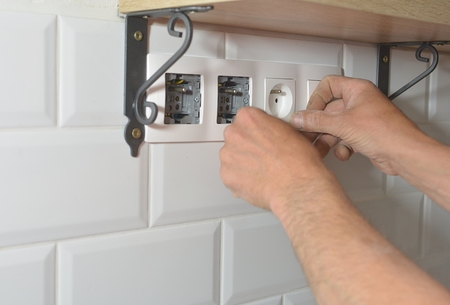 Electrician installing wall socket in new building,