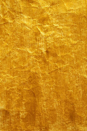 Golden color painted crinkled paper as backgroundの写真素材