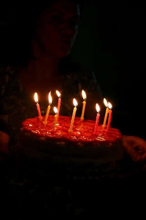 Candles, lights at a birthday cake in darkの写真素材