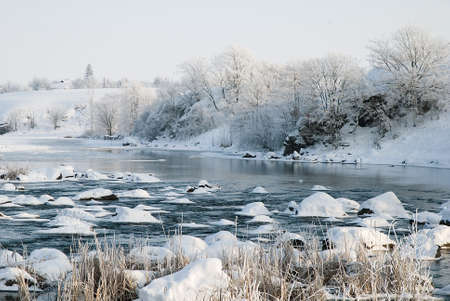 Winter landscape on the river with a stone ridge and trees covered with frostの写真素材