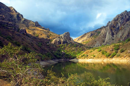 Mountain lake with rocks in the sky with dark clouds. National Park Zelenogorye. Crimea. Ukraineの写真素材