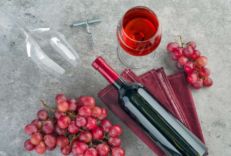 Bottle of wine,  glass of wine and  bunch of pink grapes on gray textured background. Top view.の写真素材