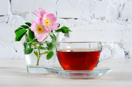 Cup of rosehip tea and rosehip flowers on white wooden table. Ð¡lose up.の写真素材