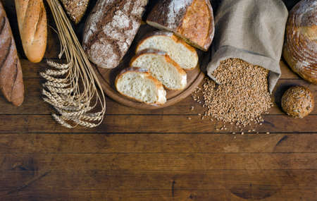 Assortment bread products, ears and grains of wheat on wooden table with copy space for your text. Rustic style, top view.の写真素材