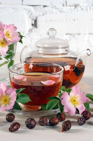 Teapot and cup of tea with rosehips on white wooden table. Ð¡lose up.の写真素材