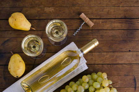 Two glasses with wine, a bottle of wine and ripe pears on wooden table with copy space for your text. Top view. Flat lay.の写真素材